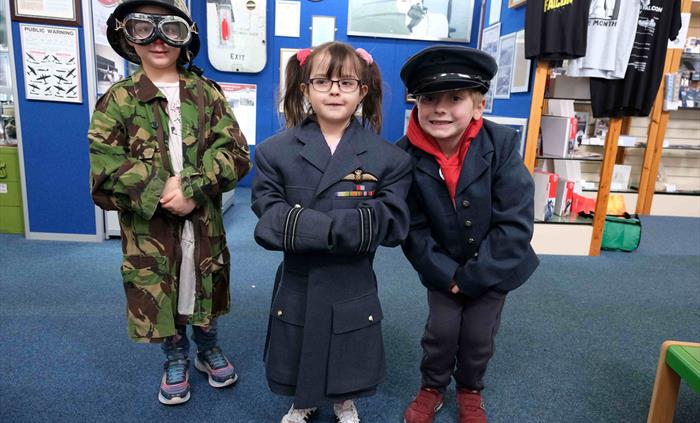 Three children enjoying dressing up in uniforms from our rummage box